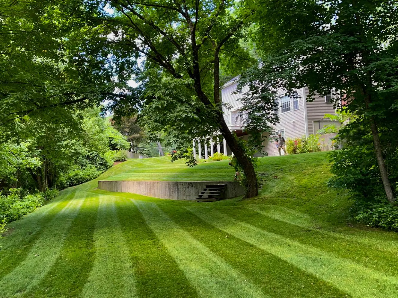 Precision-striped hillside lawn with retaining wall