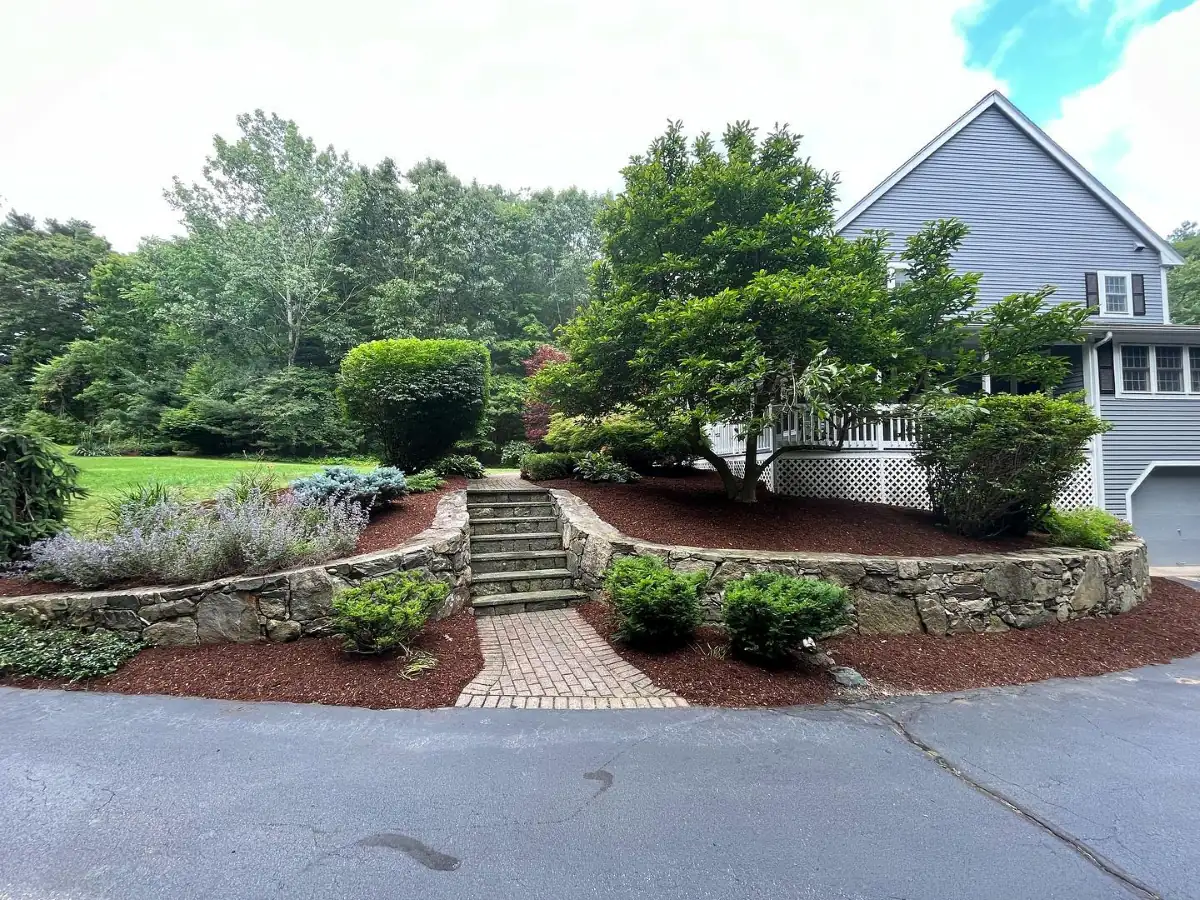 Stone retaining walls with brick walkway and mature plantings