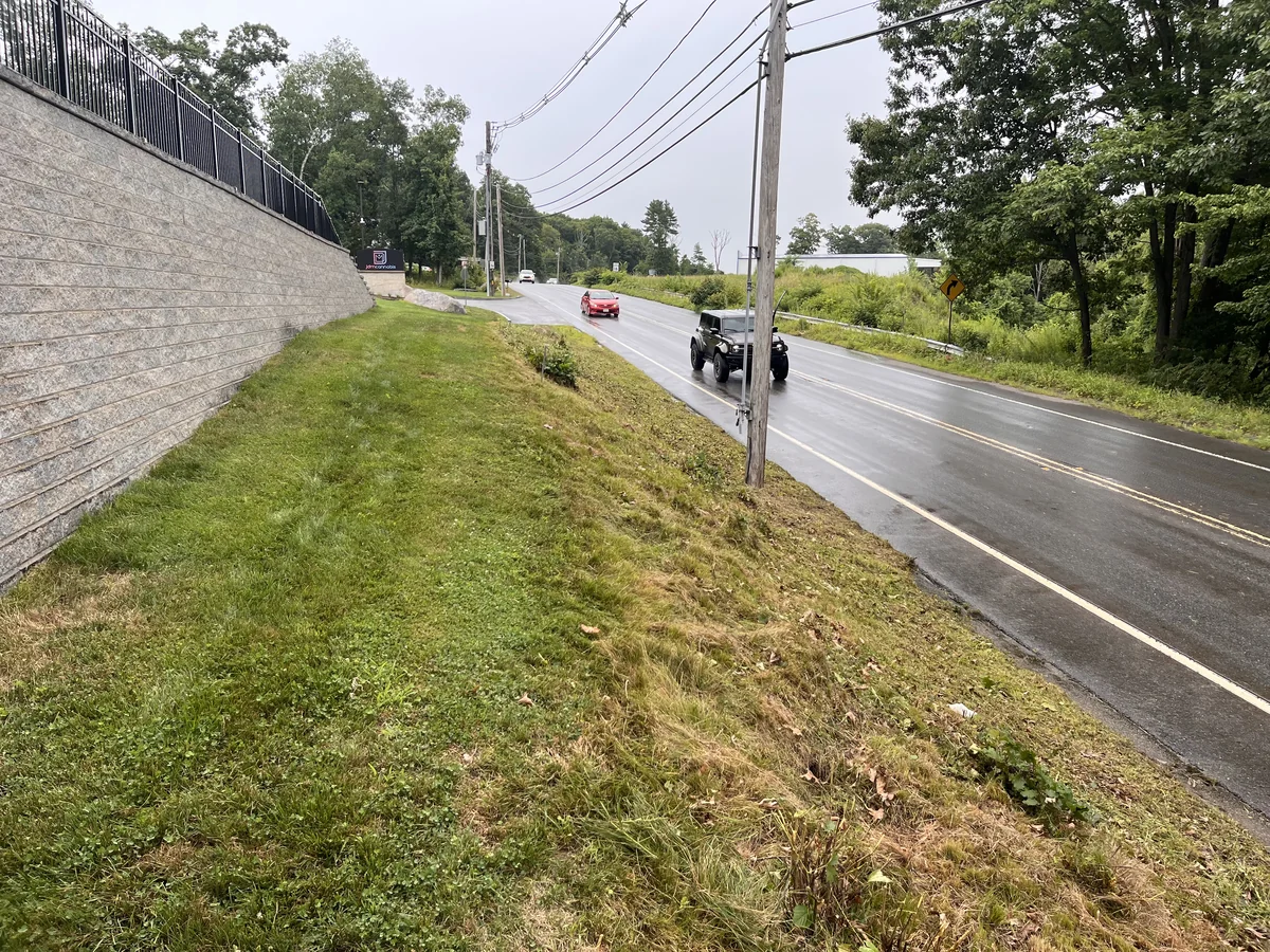 Commercial roadside embankment brush cleared to clean maintained lawn edge - After