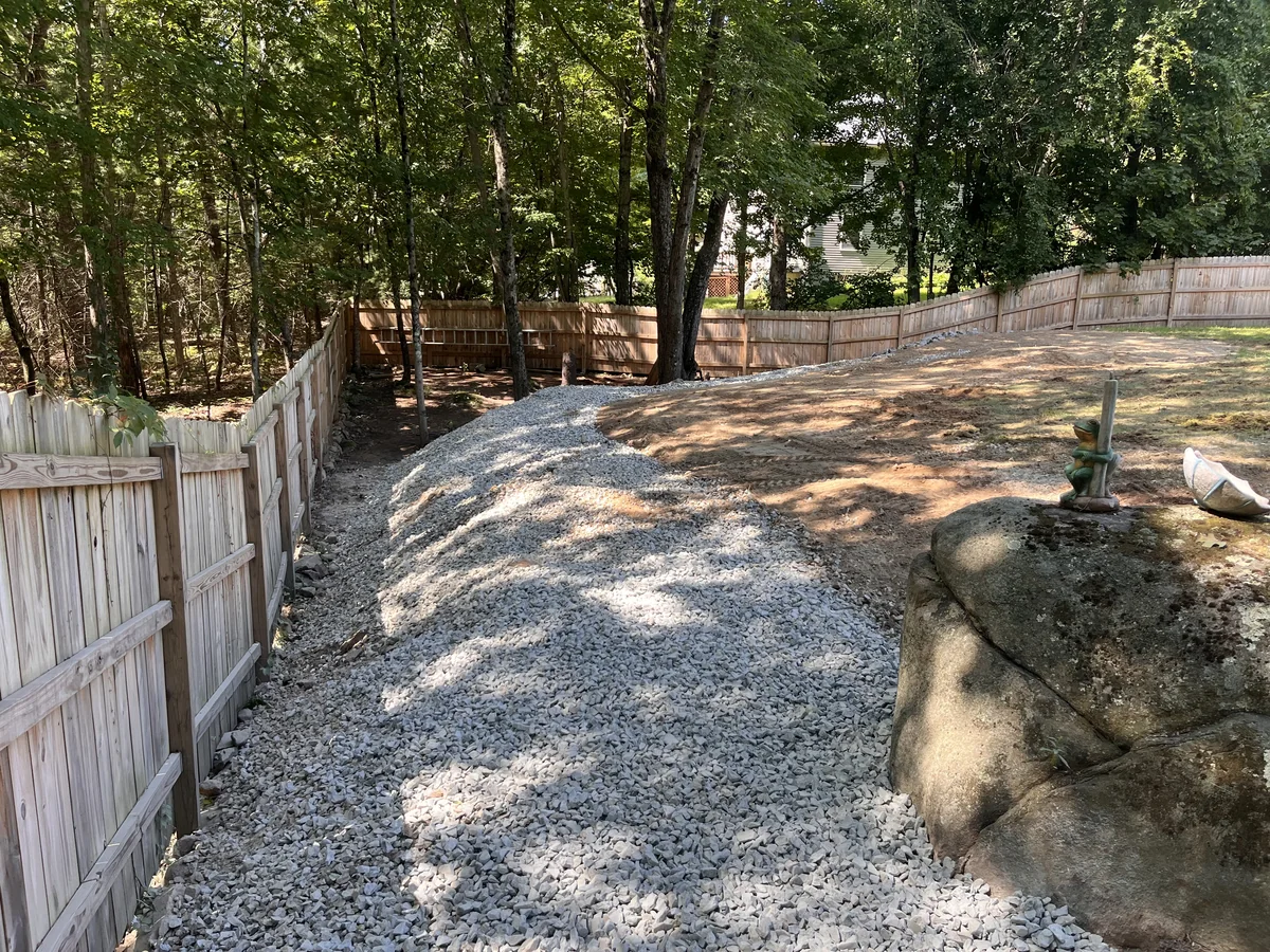 Fenced backyard gravel delivered and spread into a clean, level surface - After