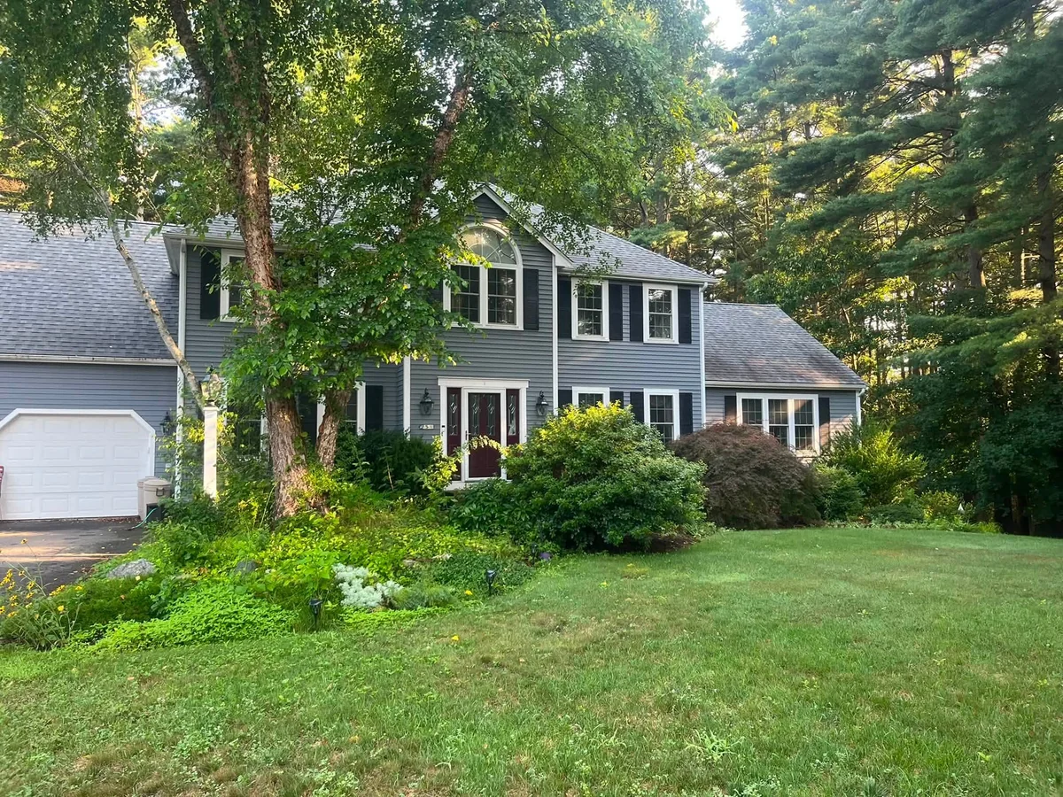 Overgrown colonial front yard shrubs and beds pruned and cleaned up - Before